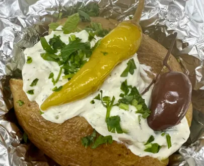 Folienkartoffel – Perfekt gegarte Kartoffel mit Knoblauchsauce, Kräutersauce oder Tzatziki, serviert auf einem Teller.