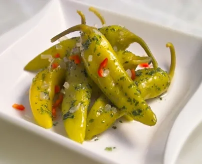 A boll of with Green peppers with stems in herb garlic.