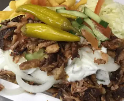 Gyros Teller (Größe) mit Zwiebeln, Tomaten, Gurken, Peperoni & zwei Beilagen nach Wahl – serviert mit Sauce auf einem Teller.